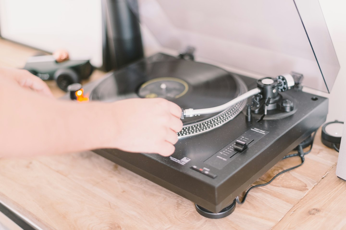 Händer som placerar en pickup på en snurrande vinylskiva.